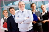 Image of senior leader smiling at camera with several employees behind